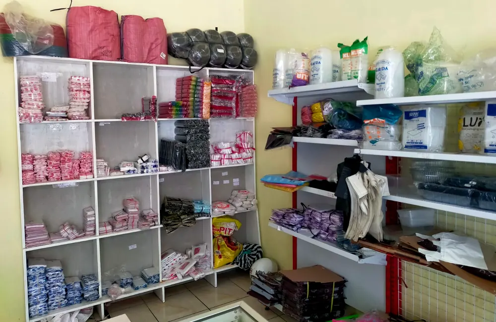 Rak penuh plastik kemasan dan wadah makanan di dalam Safira 99